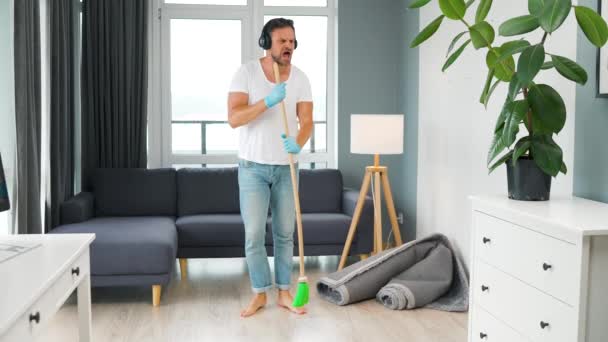 Hombre Caucásico Auriculares Limpiando Casa Divirtiéndose Bailando Cantando Con Una — Vídeo de stock