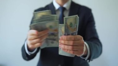 Resmi olarak giyinmiş bir adam Amerikan dolarlarını sayıyor, yakın plan. Yatırım, başarı, finansal beklentiler veya kariyer ilerlemesi kavramı