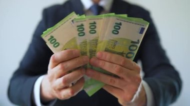 Resmi olarak giyinmiş bir adam Euro banknotlarını sayıyor, yakın plan. Yatırım, başarı, finansal beklentiler veya kariyer ilerlemesi kavramı