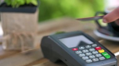 NFC kredi kartı ödemesi. NFC teknolojisiyle bağlantısız kredi kartıyla ödeme yapan bir kadın bir kafedeki banka terminalinden sipariş veriyor. Elektronik paranın banka hizmetleri. Kablosuz para aktarımı