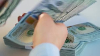 Kadın eli ya Amerikan dolarlarını sayıyor ya da nakit ödüyor. Yatırım, başarı, finansal beklentiler veya kariyer ilerlemesi kavramı