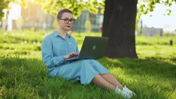 Зайнята Приваблива Жінка Працює Ноутбуці Сидить Траві Міському Парку Заході — стокове відео