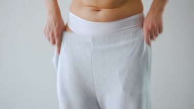 Woman puts on her pants. Concept of good health, healthy digestion and bowel function