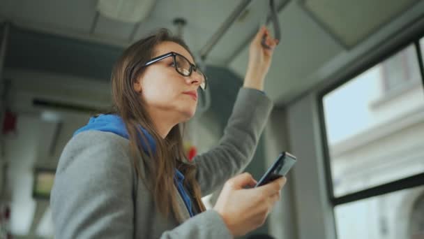 公共交通 在旅途中 戴眼镜的妇女使用智能手机与朋友聊天和发短信 — 图库视频影像