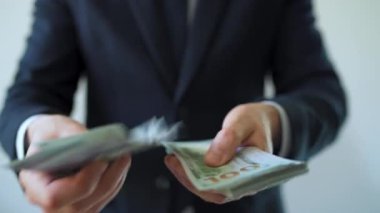 Resmi olarak giyinmiş bir adam Amerikan dolarlarını sayıyor, yakın plan. Yatırım, başarı, finansal beklentiler veya kariyer ilerlemesi kavramı