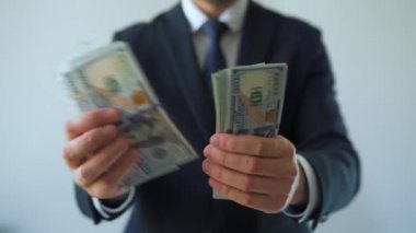Resmi olarak giyinmiş bir adam Amerikan dolarlarını sayıyor, yakın plan. Yatırım, başarı, finansal beklentiler veya kariyer ilerlemesi kavramı