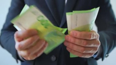Resmi olarak giyinmiş bir adam Euro banknotlarını sayıyor, yakın plan. Yatırım, başarı, finansal beklentiler veya kariyer ilerlemesi kavramı