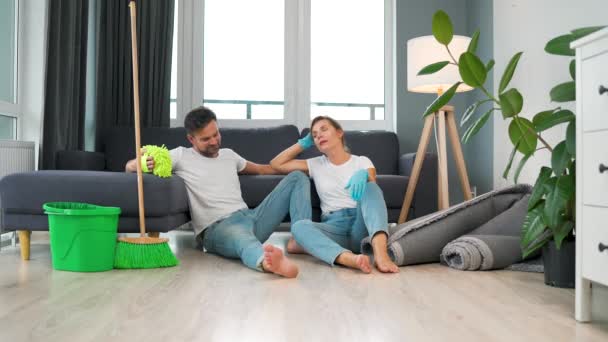 男と女は部屋の床の上に座り 家の掃除が終わると5人ずつ高い位置に座る 疲れているが幸せ スローモーション — ストック動画