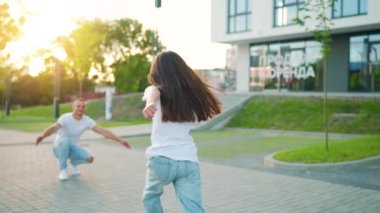 Kızı babasına koşuyor ve ona sarılıyor. Baba çocuğu kollarına alır. Ebeveyn sevgisi ve aile mutluluğu kavramı. Yavaş çekim