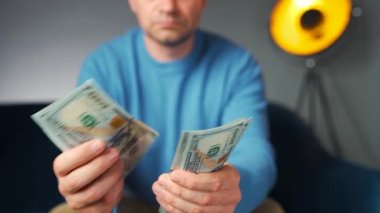 Amerikan dolarlarını sayan ya da nakit ödeyen bir adam. Yatırım, başarı, finansal beklentiler veya kariyer ilerlemesi kavramı.