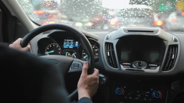 男は雨の中 市内の道路に沿って車を運転する 市内の交通 信号機の周り ドライバーの肩の後ろからの眺め — ストック動画