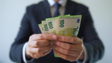 Resmi olarak giyinmiş bir adam Euro banknotlarını sayıyor, yakın plan. Yatırım, başarı, finansal beklentiler veya kariyer ilerlemesi kavramı