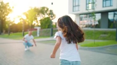 Kızı babasına koşuyor ve ona sarılıyor. Baba çocuğu kollarına alır. Ebeveyn sevgisi ve aile mutluluğu kavramı.