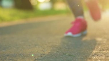 Gün batımında yürürken ya da koşarken ayakkabı bağcıklarını bağlayan kadın, kapat..