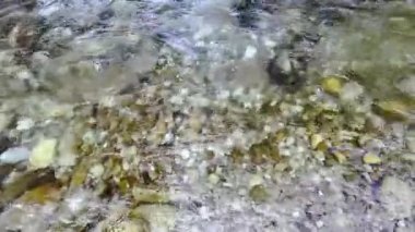 Surface of a mountain creek with crystal clear mountain water, stones at the bottom. Summer coolness