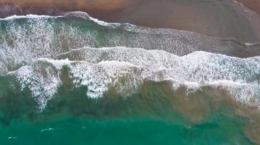 Deniz dalgaları kumlu sahil şeridinde dalgalanırken hiç bitmeyen güzel ve kusursuz görüntülerin drone görüntüsü. Akdeniz kıyısının en üst manzarası, dalgalar ıssız kumsala ulaşıyor. Güzel