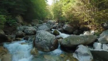 Fast flight over a mountain river flowing among large stones and surrounded by trees on the banks. Tatra Mountains, Slovakia. POV filmed with FPV drone.