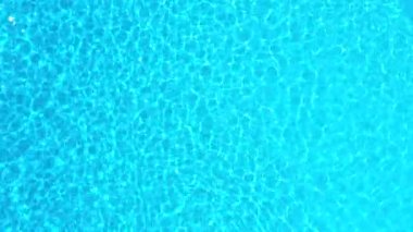 Yüzme havuzundaki saf mavi suyun yüzeyinde ışık yansımaları var. Hava görüntüleri
