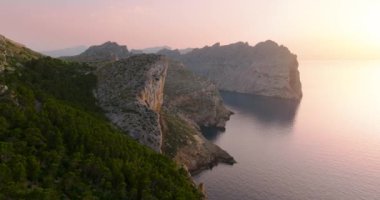 Scenic aerial view of a mountainous region in Majorca with cliffs. Panoramic view of a sunset over Mirador Es Colomer in Sierra de Tramuntana and blue sea, Balearic Islands, Spain.
