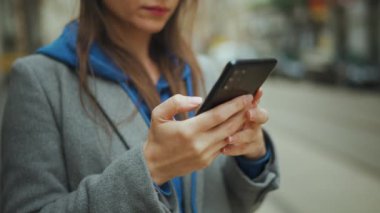 Woman stands at a public transport stop and checks the timetable. City, urban, transportation.