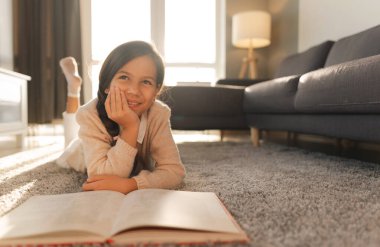 Cute girl reading a book and lying on the floor. Education and school concept.