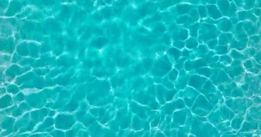 Yüzme havuzundaki saf mavi suyun yüzeyinde ışık yansımaları var. Hava görüntüleri