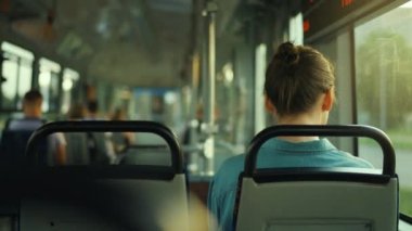 Public transport. Woman with glasses in a tram looking out the window. Back view. City, urban, transportation. Slow motion