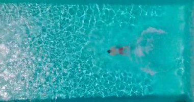 Top down view as a man dives into the pool and swims. Slow motion