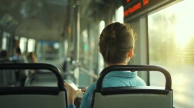 Public transport. Woman in glasses in tram using smartphone chatting and texting with friends, slow motion. Back view. City, urban, transportation.