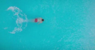 Top down view as a man dives into the pool and swims. Slow motion