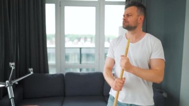 Adam evi temizliyor, dans ediyor ve süpürgeyle şarkı söylüyor.. 