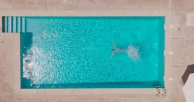 Top down view as a man dives into the pool and swims. Slow motion