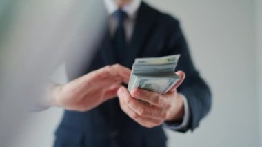 Formally dressed man makes money rain from US dollar bills. Slow motion. Concept of investment, success, financial prospects or career advancement