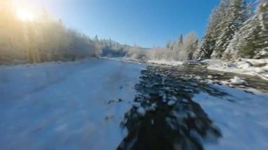 Fast flight along a mountain river surrounded by a snow-covered forest. Fairy winter mountain landscape on a frosty sunny day. Tatra Mountains, Zakopane, Poland. Filmed on FPV Drone