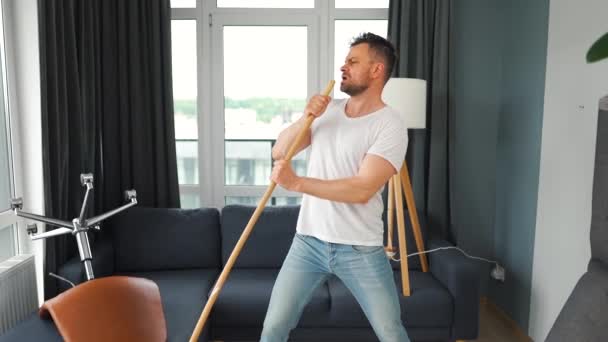 男人打扫房子 一边跳舞一边用扫帚唱歌 慢动作 — 图库视频影像