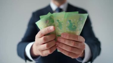 Resmi olarak giyinmiş bir adam Euro banknotlarını sayıyor, yakın plan. Yatırım, başarı, finansal beklentiler veya kariyer ilerlemesi kavramı.