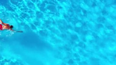Havuzda yüzen kırmızı şortlu bir adamın hava görüntüsü. Yaz yaşam tarzı