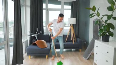 Adam evi temizliyor, dans ediyor ve süpürgeyle şarkı söylüyor.. 