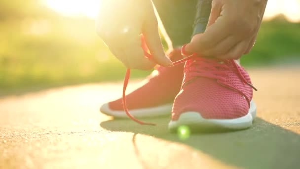 ジョギングや日没時に歩いている間に靴ひもを結ぶ女性 閉じる — ストック動画