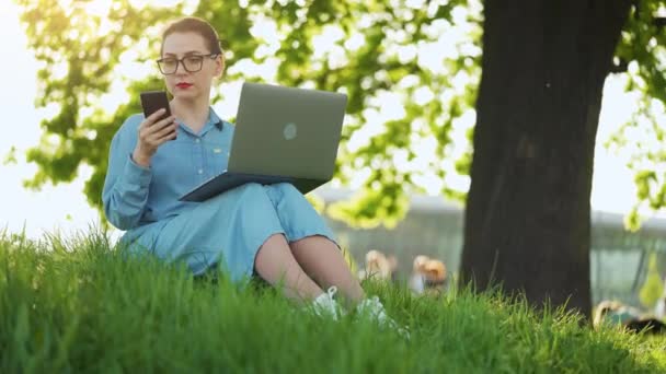 Elfoglalt Vonzó Dolgozik Laptopon Használja Okostelefon Miközben Füvön Városi Parkban — Stock videók