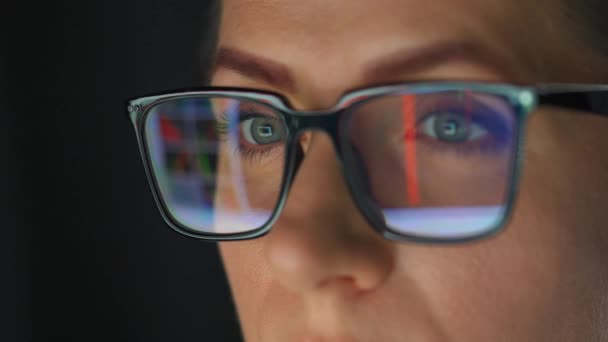 戴眼镜的女人看着监视器 用图表和分析仪器工作 显示器屏幕反映在眼镜上 晚上工作 极端密切的情况 — 图库视频影像
