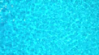 Yüzme havuzundaki saf mavi suyun yüzeyinde ışık yansımaları var. Hava görüntüleri