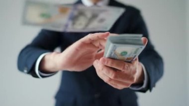 Formally dressed man makes money rain from US dollar bills. Slow motion. Concept of investment, success, financial prospects or career advancement