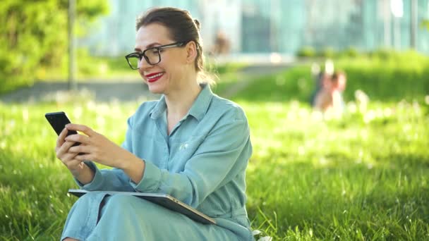 妇女在日落时完成室外工作后 坐在公园里使用智能手机 在室外工作的自由职业者 — 图库视频影像