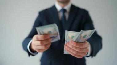 Resmi olarak giyinmiş bir adam Amerikan dolarlarını sayıyor, yakın plan. Yatırım, başarı, finansal beklentiler veya kariyer ilerlemesi kavramı.