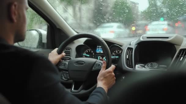 人在雨中驾驶一辆汽车沿着城市的道路行驶 周围的城市交通 红绿灯 从司机后面看 — 图库视频影像