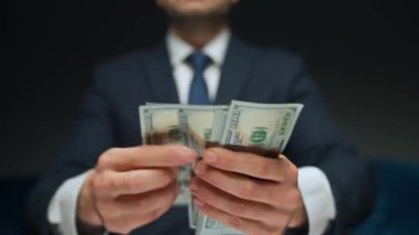 Resmi olarak giyinmiş bir adam Amerikan dolarlarını sayıyor, yakın plan. Yatırım, başarı, finansal beklentiler veya kariyer ilerlemesi kavramı.
