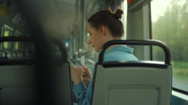 Toplu taşıma. Tramvaydaki gözlüklü kadın akıllı telefon konuşmaları yapıyor ve arkadaşlarıyla mesajlaşıyor. Arkadan bak. Şehir, şehir, ulaşım.