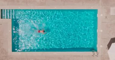 Havuzda yüzen bir adam olarak tepeden aşağı bir manzara. Yavaş çekim