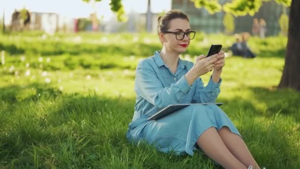 Mujer Usando Smartphone Mientras Está Sentado Parque Después Terminar Trabajo — Vídeos de Stock